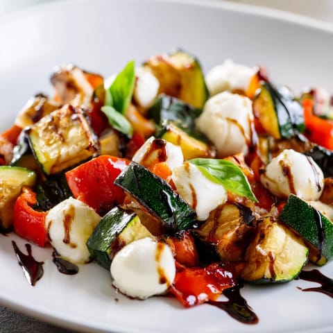 Roasted Veggie Caprese Salad served warm on a platter with caramelized veggies, creamy cheese, and torn basil garnish.