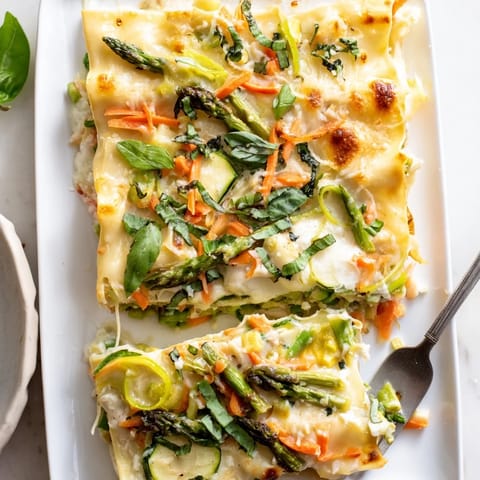 Baked Spring Veggie Alfredo Lasagna with golden, bubbly mozzarella topping and fresh basil garnish.
