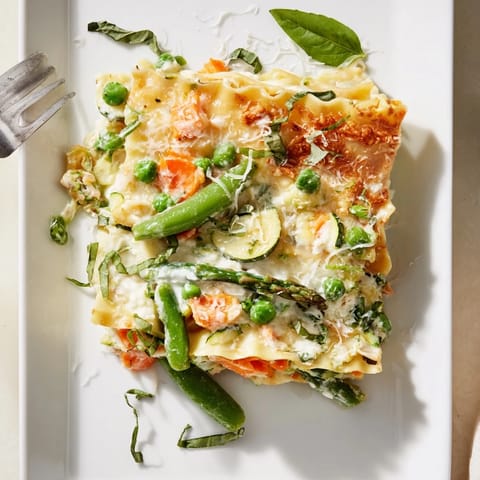 A slice is lifted to reveal layers of creamy ricotta, tender asparagus, and snap peas.