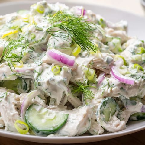 A close-up of vibrant, chilled Creamy Cucumber Chicken Salad tossed in creamy dill yogurt dressing, garnished with green onions for a perfect potluck meal.