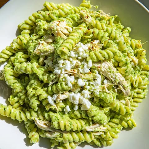 Tender rotini noodles and juicy chicken coated in tangy cilantro lime sauce, garnished with fresh cilantro and lime wedges.