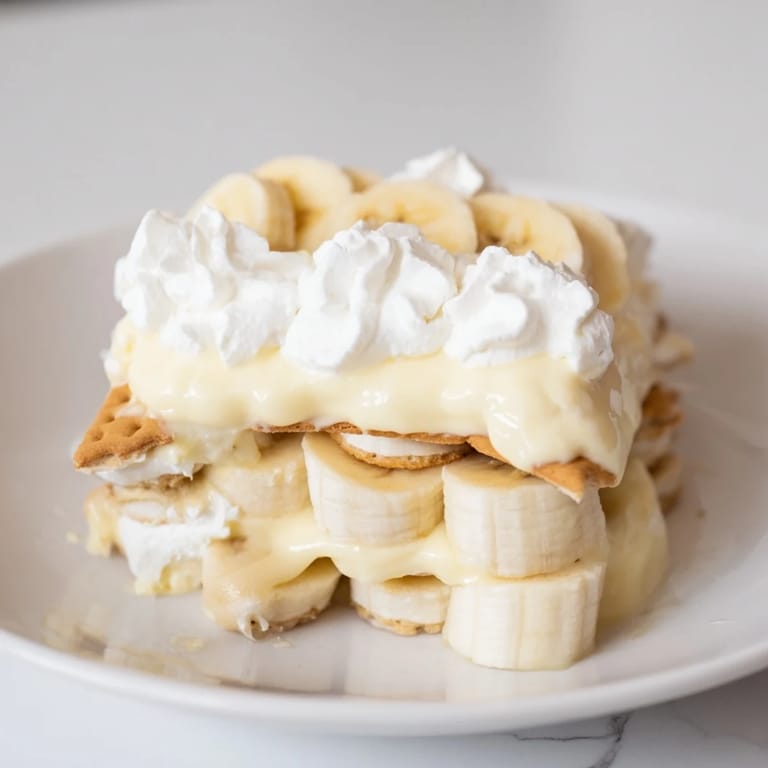 Golden-yellow Banana Pudding filling brimming with ripe banana slices and crisp vanilla wafers in a glass bowl.