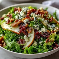 Fresh, crisp frisée and sliced ripe pears topped with crumbled blue cheese and crispy prosciutto in a Frisée Pear Blue Cheese Bowl.